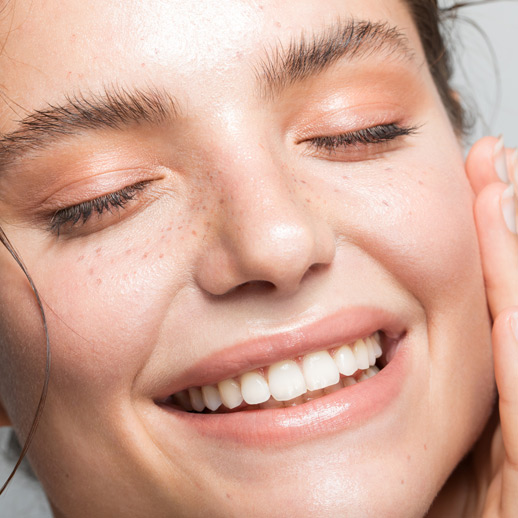 woman-smiling-with-natural-glowing-skin-and-closed-eyes