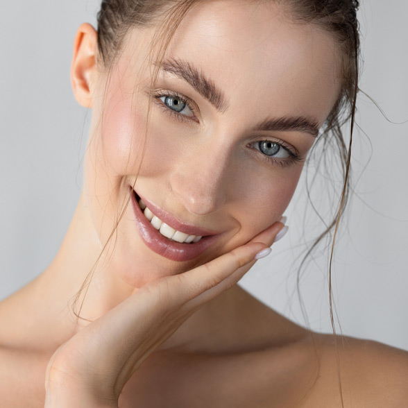 woman-with-clear-radiant-skin-smiling-and-touching-her-face-gently