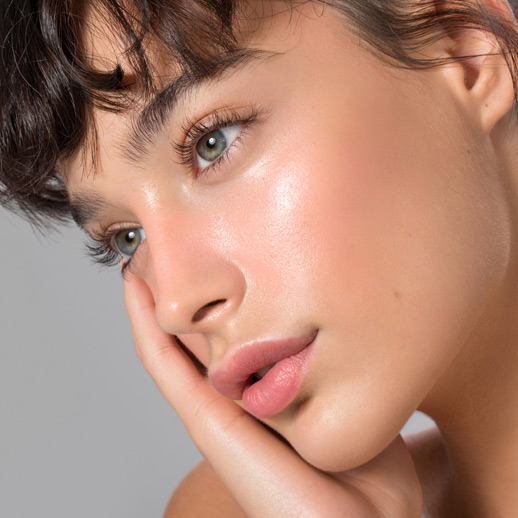 woman-with-dewy-glowing-skin-resting-her-face-on-hand