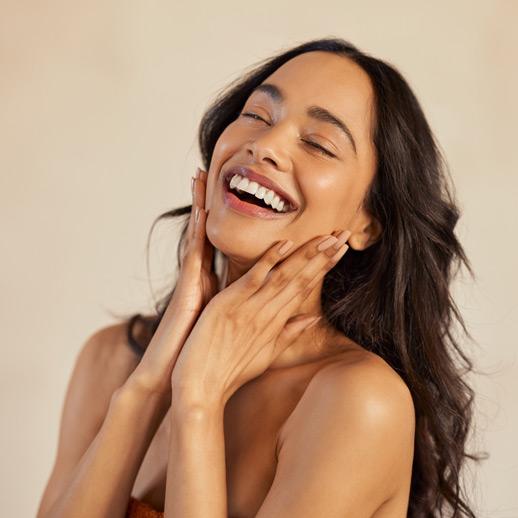 woman-with-glowing-skin-laughing-joyfully-and-touching-her-face