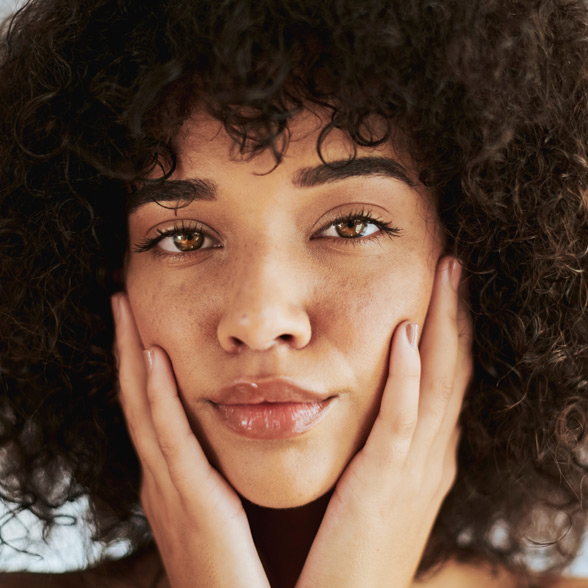 woman-with-natural-curly-hair-touching-her-face