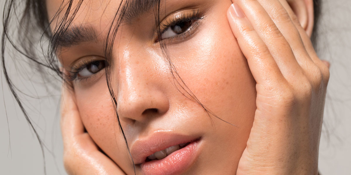 Close-up-of-woman-framing-face-with-hands-showing-luminous-healthy-skin
