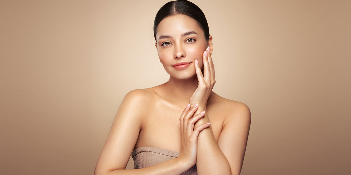 Woman gently touching cheek with even glowing skin and healthy radiance