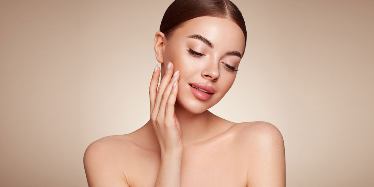 Woman gently touching cheek with radiant even toned skin