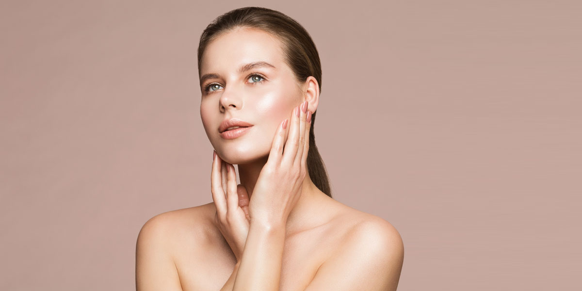 Woman gently touching face showcasing luminous even skin