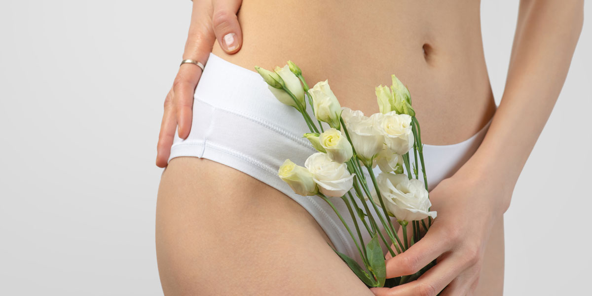 Woman holding flowers near lower abdomen in underwear