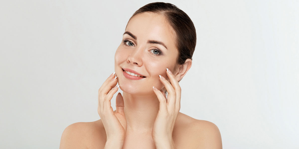 Woman touching face with soft healthy glowing skin