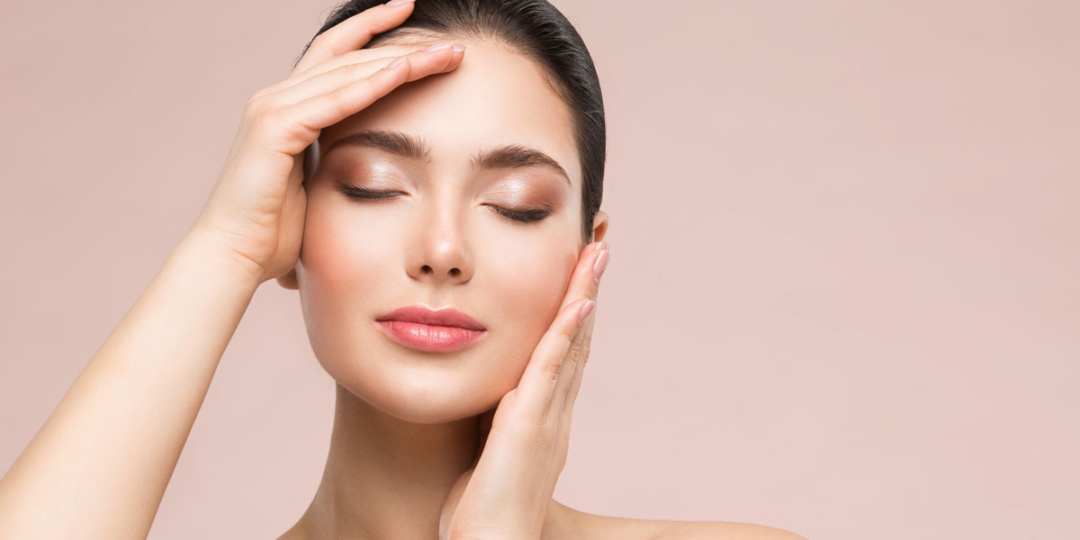 Woman-with-eyes-closed-gently-holding-face-showing-smooth-glowing-skin