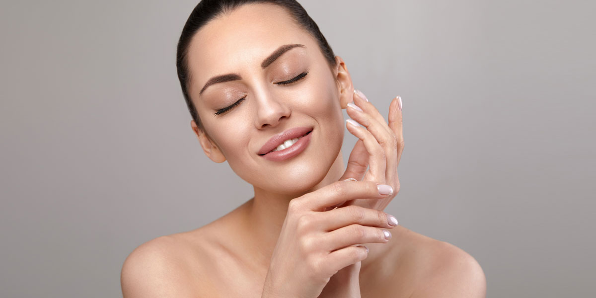 Woman with eyes closed gently touching face showing smooth glowing skin