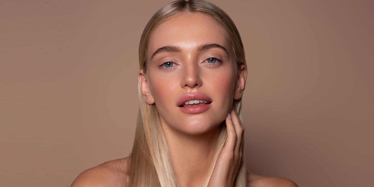 Woman with luminous skin lightly touching her neck