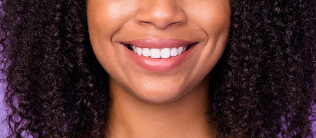 smiling-woman-in-a-striped-top-against-a-purple-background