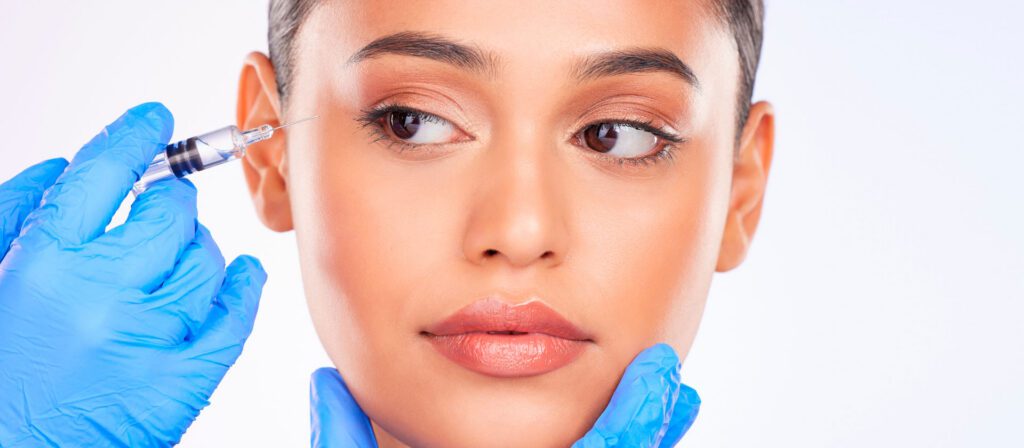 woman-receiving-a-cosmetic-injection-near-her-eye-from-a-gloved-provider