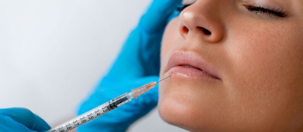 woman-with-her-eyes-closed-receiving-an-injection-near-her-lips