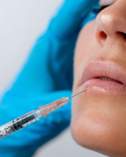 woman-with-her-eyes-closed-receiving-an-injection-near-her-lips