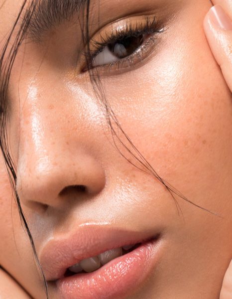 Close up of woman framing face with hands showing luminous healthy skin
