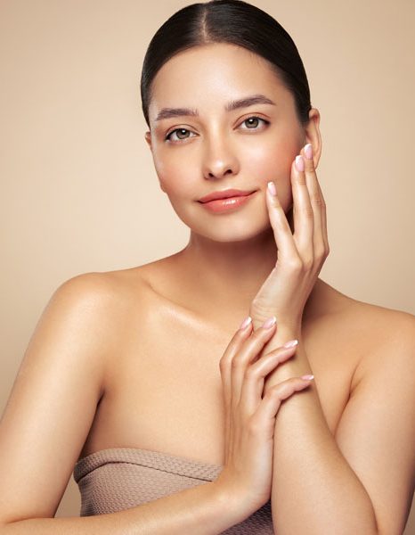 Woman gently touching cheek with even glowing skin and healthy radiance