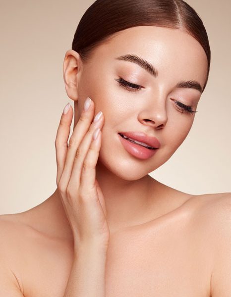 Woman gently touching cheek with radiant even toned skin