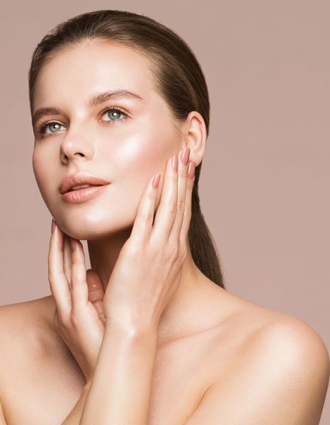 Woman gently touching face showcasing luminous even skin