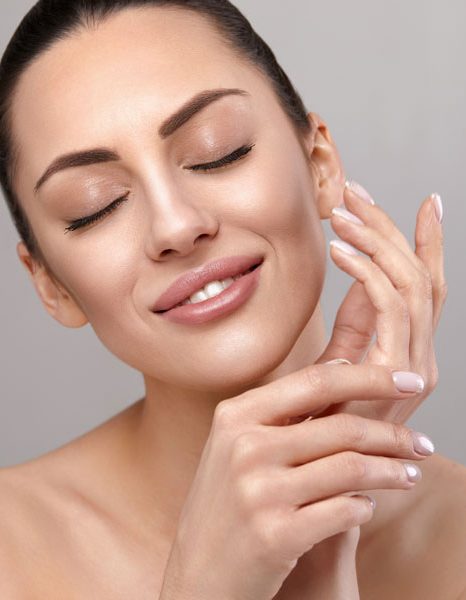 Woman with eyes closed gently touching face showing smooth glowing skin