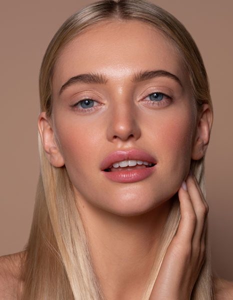 Woman with luminous skin lightly touching her neck